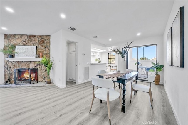 dining space with light hardwood / wood-style flooring and a stone fireplace