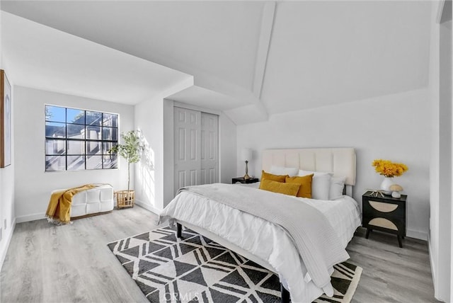 bedroom featuring vaulted ceiling, a closet, and light hardwood / wood-style floors