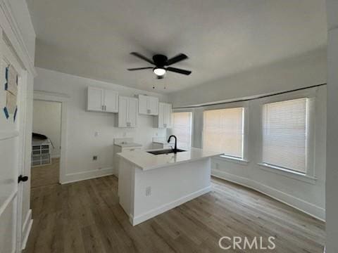 kitchen with sink, white cabinets, ceiling fan, hardwood / wood-style flooring, and a kitchen island with sink