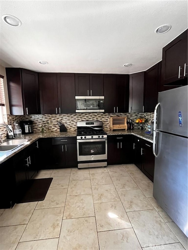 kitchen with tasteful backsplash, sink, dark brown cabinetry, stainless steel appliances, and light stone counters