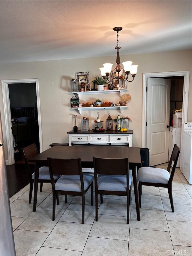 dining area featuring light tile patterned flooring, an inviting chandelier, and washing machine and clothes dryer