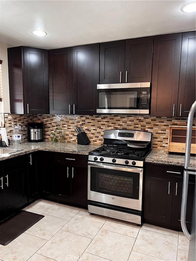 kitchen featuring tasteful backsplash, light stone counters, and stainless steel appliances