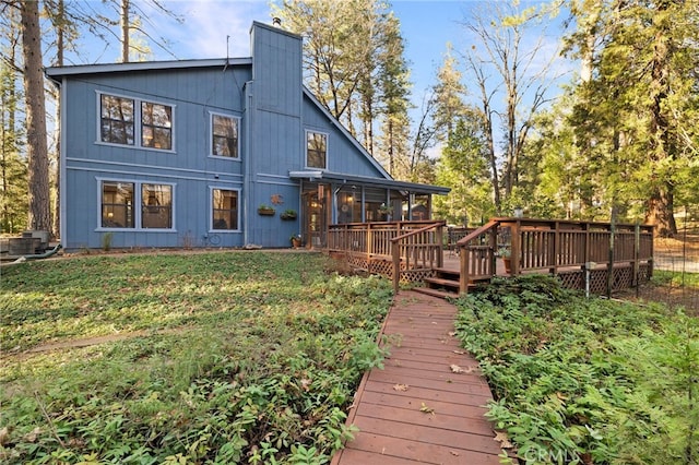 rear view of house with a lawn, a sunroom, and a wooden deck