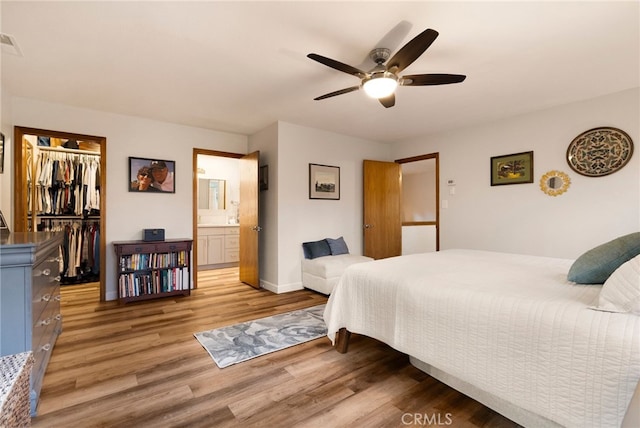 bedroom with ensuite bath, a closet, hardwood / wood-style floors, a walk in closet, and ceiling fan