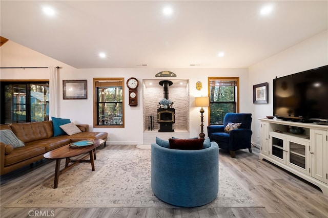 living room featuring light wood-type flooring, a wood stove, and a healthy amount of sunlight