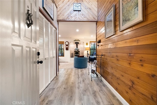 corridor with light wood-type flooring and wooden walls