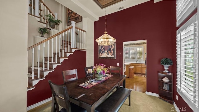 carpeted dining area with a notable chandelier and a towering ceiling