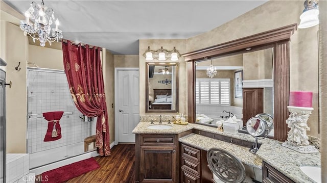 bathroom with wood-type flooring, vanity, an inviting chandelier, and independent shower and bath