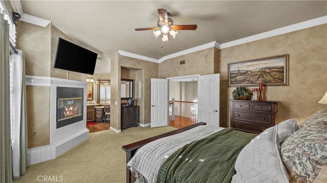 bedroom featuring ensuite bathroom, crown molding, a fireplace, ceiling fan, and light carpet