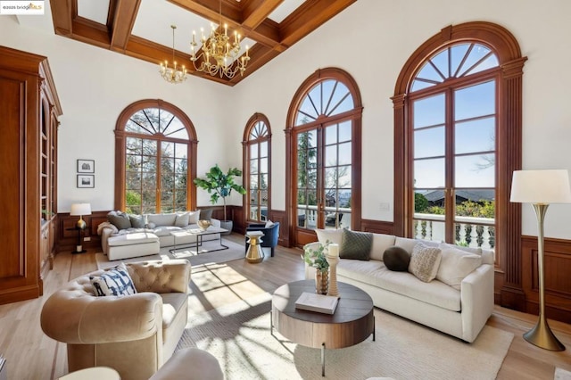 living room with coffered ceiling, light wood-type flooring, plenty of natural light, and beamed ceiling