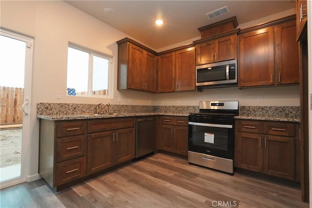 kitchen with light stone counters, sink, dark hardwood / wood-style flooring, and stainless steel appliances