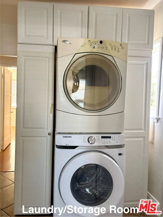 laundry room featuring cabinets and stacked washer / drying machine