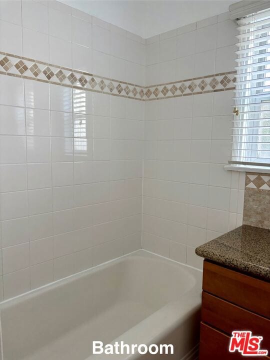 bathroom featuring tiled shower / bath combo and vanity