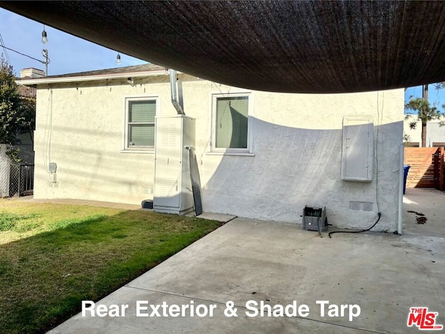 view of property exterior featuring a patio and a lawn