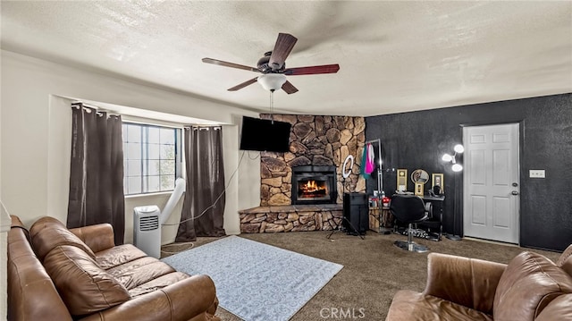 carpeted living room featuring a textured ceiling, ceiling fan, and a stone fireplace