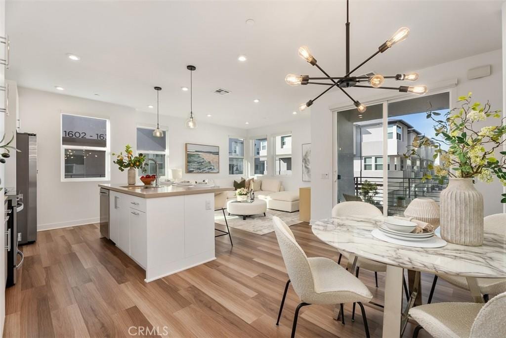 dining area featuring sink, a chandelier, and light hardwood / wood-style flooring