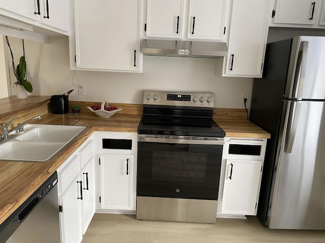 kitchen with white cabinets, appliances with stainless steel finishes, wood counters, and sink