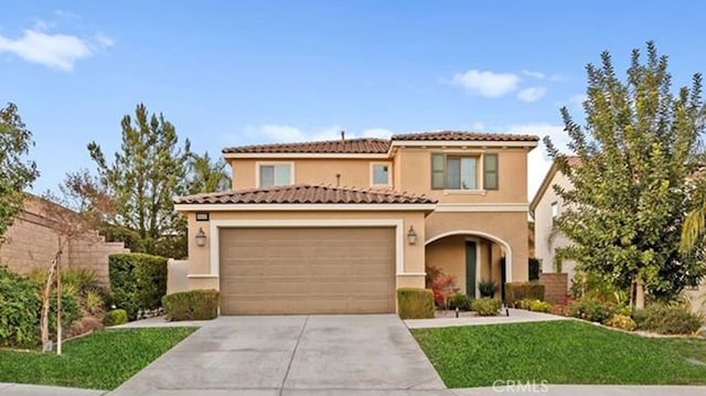 mediterranean / spanish home featuring a front yard and a garage