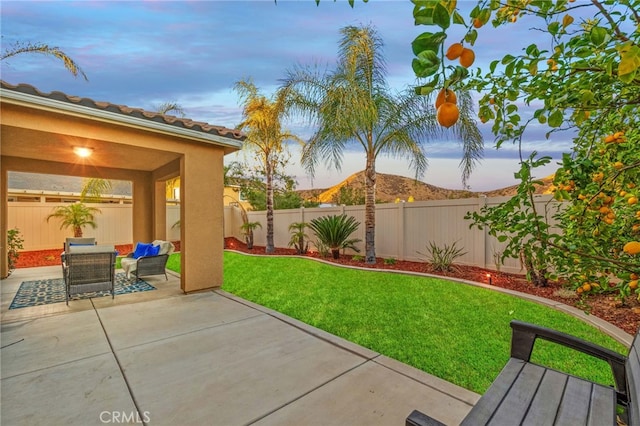 patio terrace at dusk with outdoor lounge area and a yard