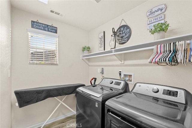 laundry room with separate washer and dryer and hardwood / wood-style flooring