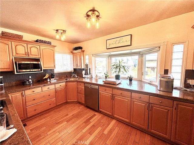 kitchen featuring stainless steel appliances, light hardwood / wood-style flooring, and decorative backsplash