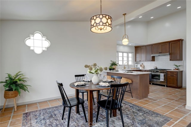 tiled dining room featuring sink and a towering ceiling