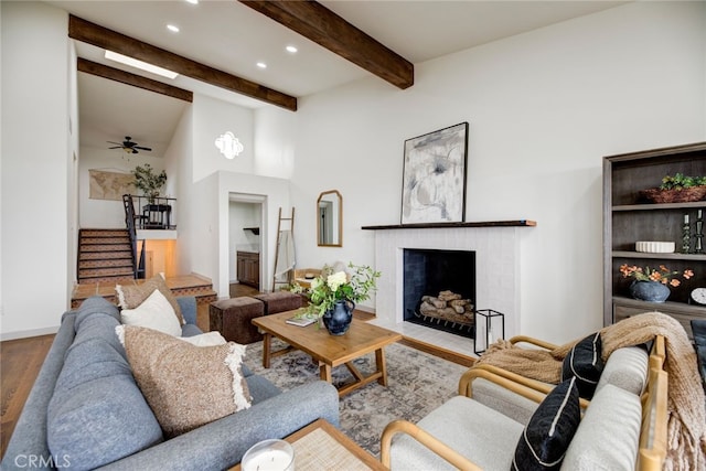 living room with a fireplace, ceiling fan, hardwood / wood-style flooring, and beamed ceiling