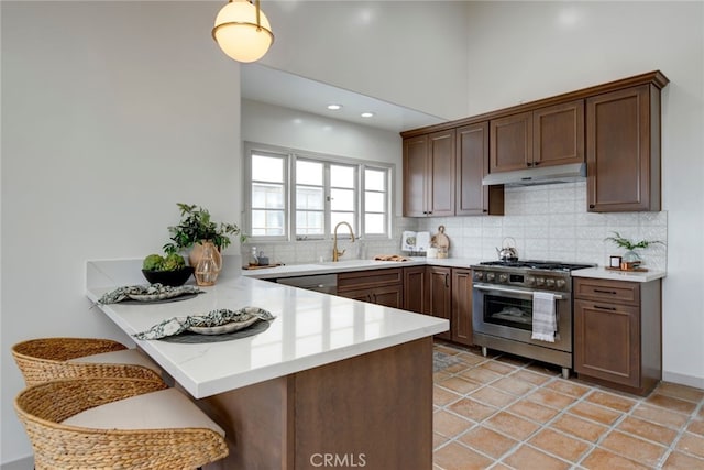 kitchen with stainless steel appliances, sink, kitchen peninsula, backsplash, and a breakfast bar