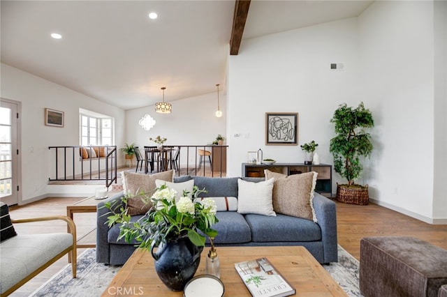 living room with wood-type flooring, lofted ceiling with beams, and a notable chandelier