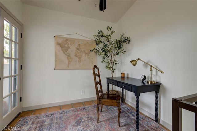 office with tile patterned floors and vaulted ceiling