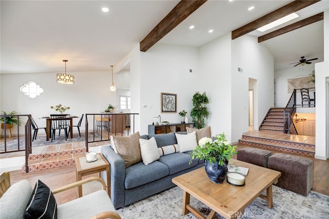 living room with ceiling fan, light hardwood / wood-style flooring, and vaulted ceiling with beams