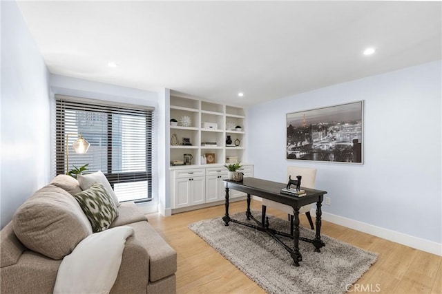 office space featuring light hardwood / wood-style floors and built in shelves