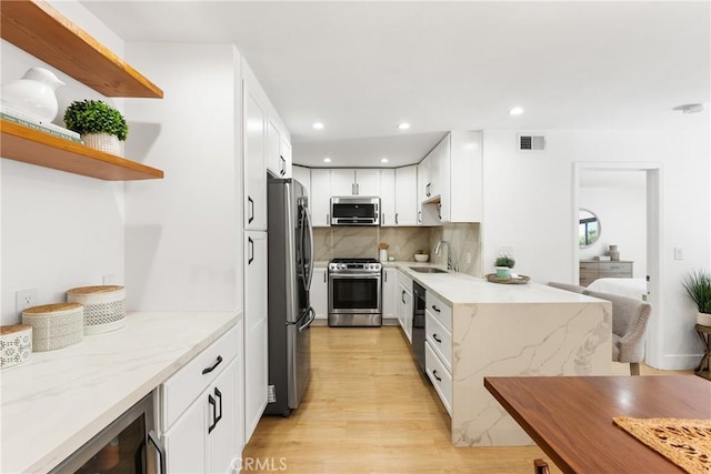 kitchen with white cabinetry, sink, wine cooler, stainless steel appliances, and light stone countertops