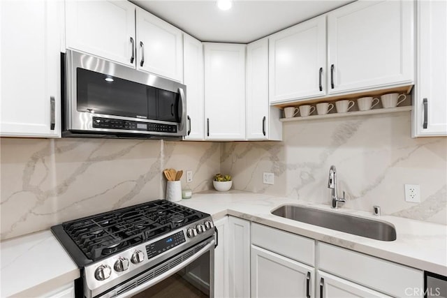 kitchen with tasteful backsplash, appliances with stainless steel finishes, sink, and white cabinets