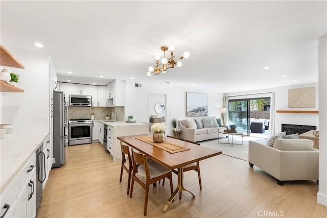 dining space featuring an inviting chandelier, sink, and light wood-type flooring