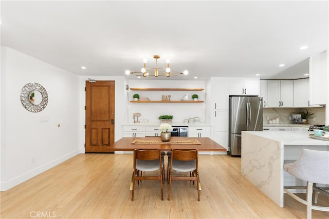 dining space with beverage cooler, a chandelier, and light wood-type flooring