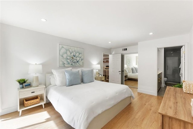 bedroom with ensuite bath and light hardwood / wood-style flooring