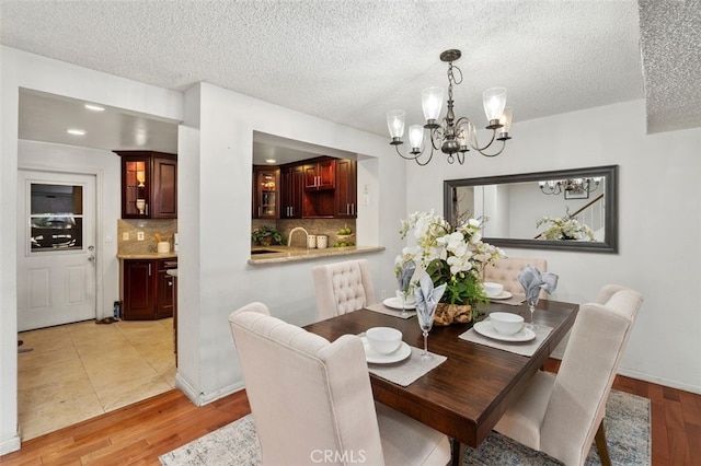 dining room with an inviting chandelier, light hardwood / wood-style floors, and a textured ceiling