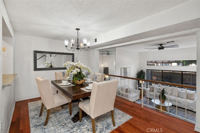 dining area featuring ceiling fan with notable chandelier, wood-type flooring, and a textured ceiling