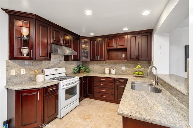 kitchen featuring white gas range, sink, light tile patterned floors, light stone counters, and kitchen peninsula