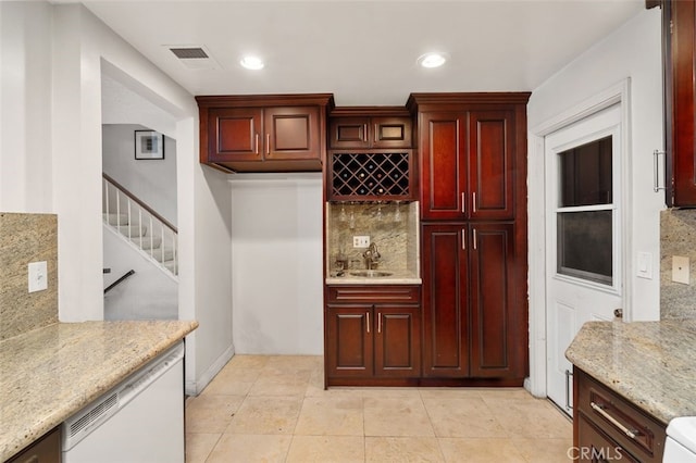 kitchen with sink, light tile patterned floors, dishwasher, light stone countertops, and backsplash