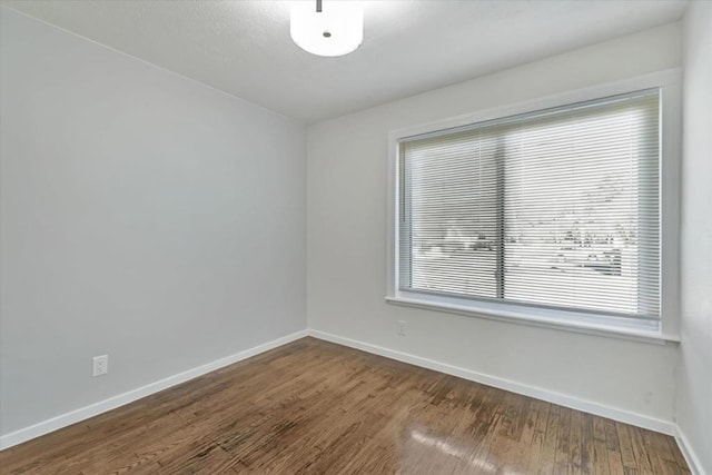 spare room with dark wood-type flooring and a wealth of natural light