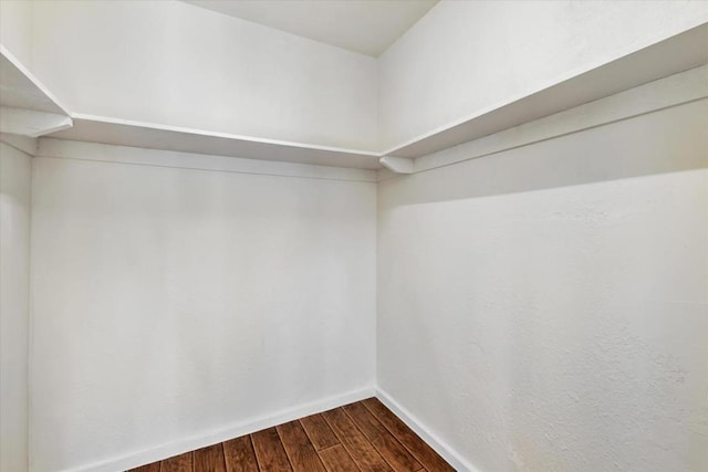 walk in closet with dark wood-type flooring