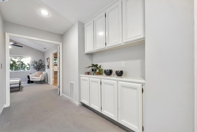 hallway featuring vaulted ceiling and light colored carpet