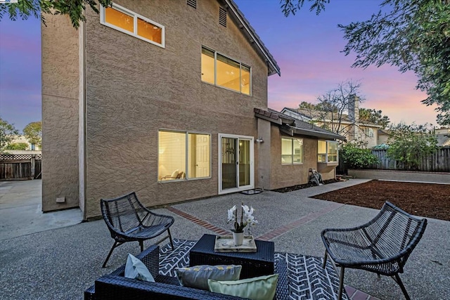 back house at dusk featuring a patio area and outdoor lounge area