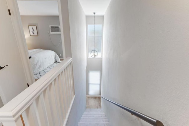 stairway featuring a notable chandelier, a wealth of natural light, and a wall mounted air conditioner