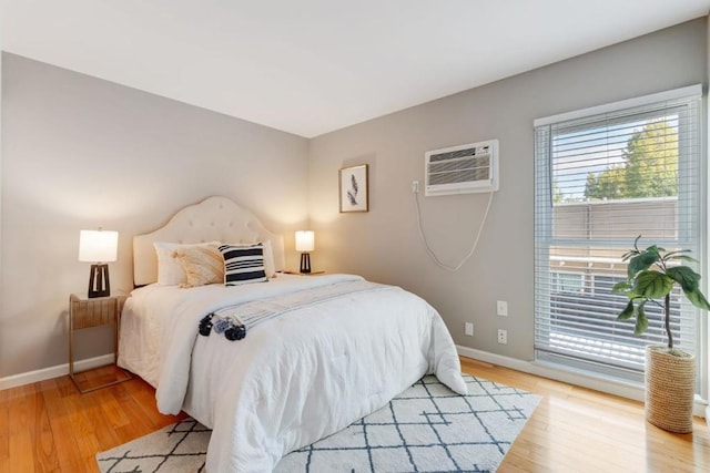 bedroom with light hardwood / wood-style flooring and a wall mounted air conditioner