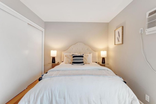 bedroom featuring a wall mounted AC, a closet, and hardwood / wood-style flooring