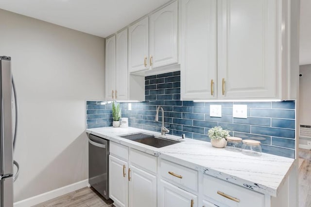 kitchen with light hardwood / wood-style floors, sink, white cabinetry, light stone countertops, and appliances with stainless steel finishes