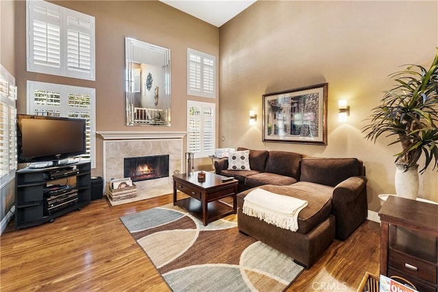 living room with a towering ceiling, a high end fireplace, and hardwood / wood-style flooring